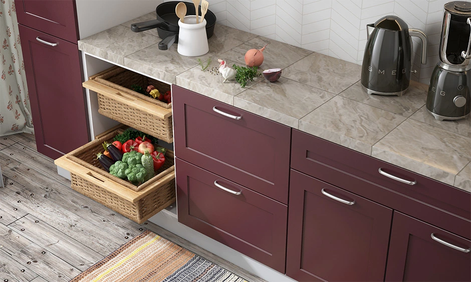 A modern kitchen with Tile Countertop, red cabinets, few kitchen appliances and vegetables in basket