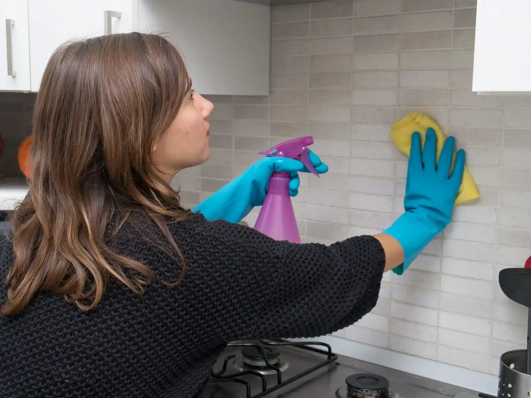 A lady cleaning Tile backsplash to remove stains