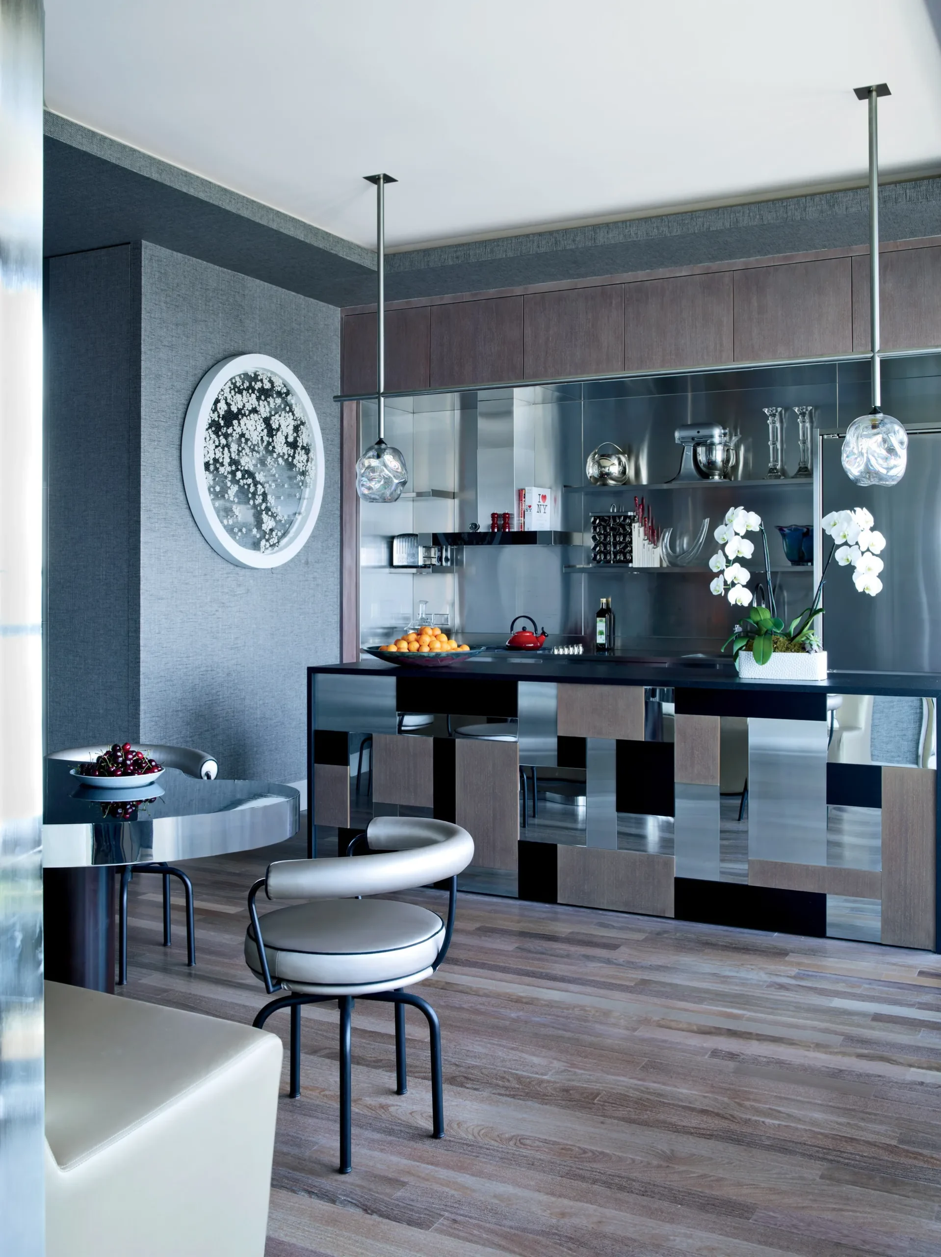 A kitchen with Marble and Metal Mix cabinets and island is covered in unlacquered brass and topped with Breccia Imperiale marble. Marble shelves are supported by brackets. An 18th-century painting of Saint Peter with vintage American barstools.