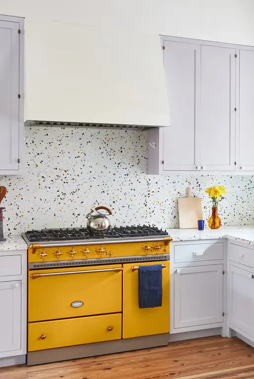 Rainbow terrazzo backsplash and matching countertop with vibrant yellow range