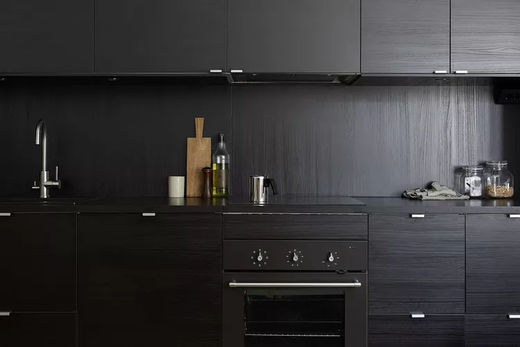 A classy and small kitchen with all-black cabinetry and matching backsplash