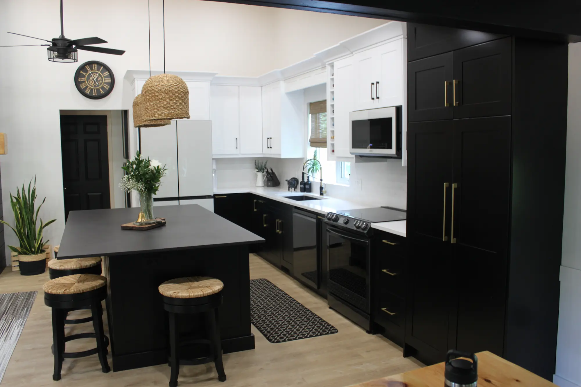 a beautiful kitchen with more cabinets in black color and few upper cabinets in white color