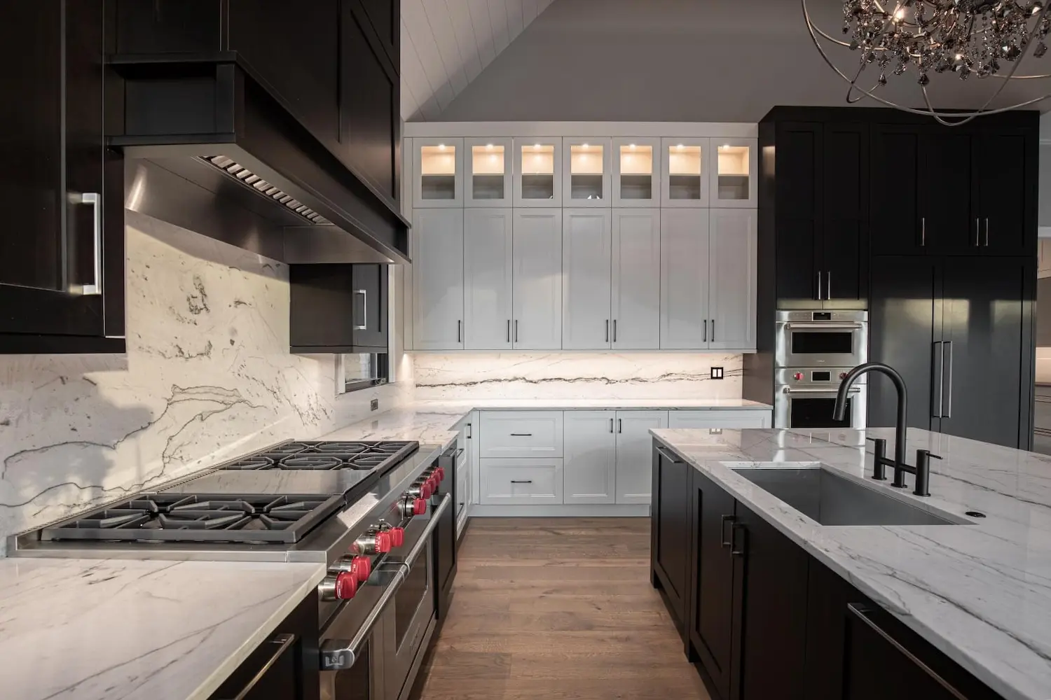 Monochromatic Black & White Cabinets in a beautiful kitchen with wood flooring and stone backsplash