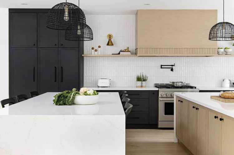 kitchen with black base cabinets with a wall of cabinets that extends to the ceiling and containing white elements and wood accents